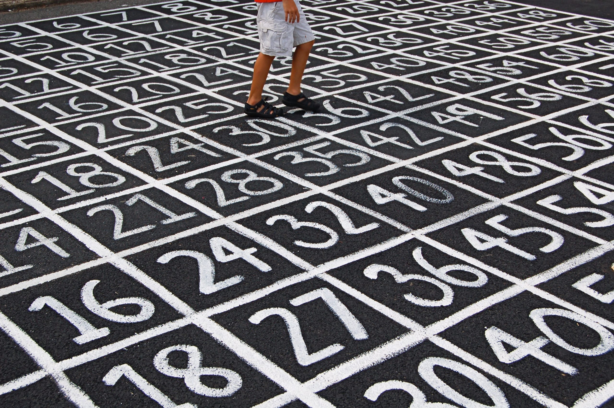 Person in shorts walking across white numbers painted on tarmac.